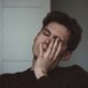 Exhausted young man rubbing his face in fatigue, illustrating the overwhelming tiredness experienced in chronic fatigue, fibromyalgia, and long COVID