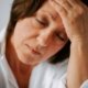 Middle-aged woman with closed eyes and hand on forehead, appearing fatigued from perimenopause, preparing to seek support through nutrition counseling covered by insurance to improve energy and hormonal balance.